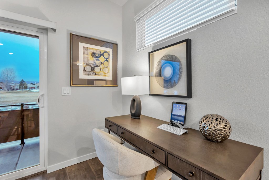 A modern home office with a desk, chair, and two framed artworks.