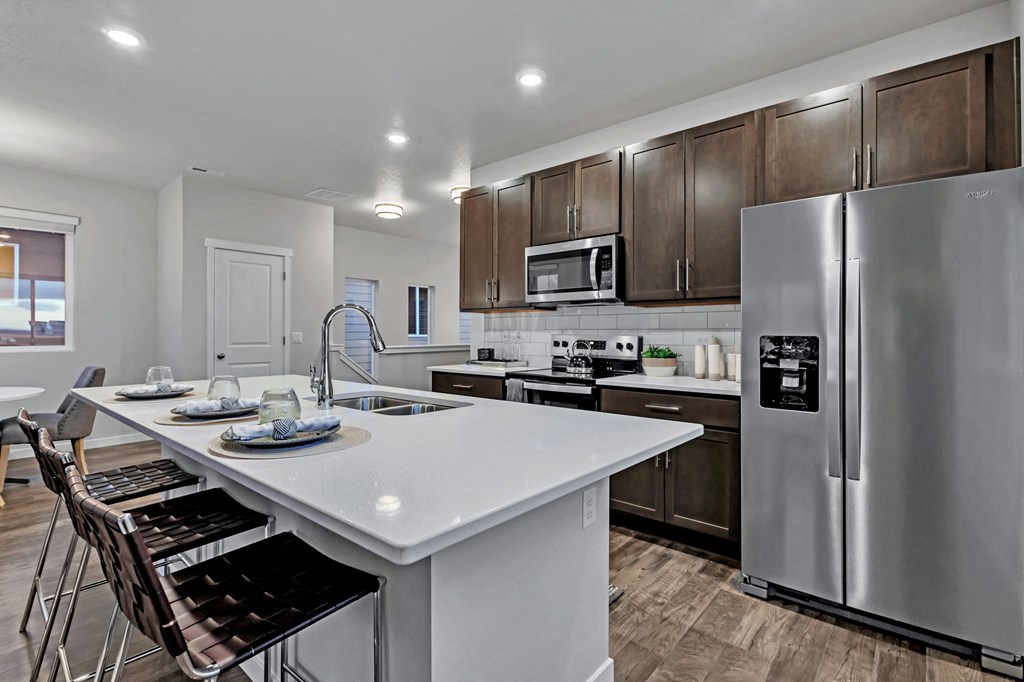 A modern kitchen with a white island and stainless steel appliances.