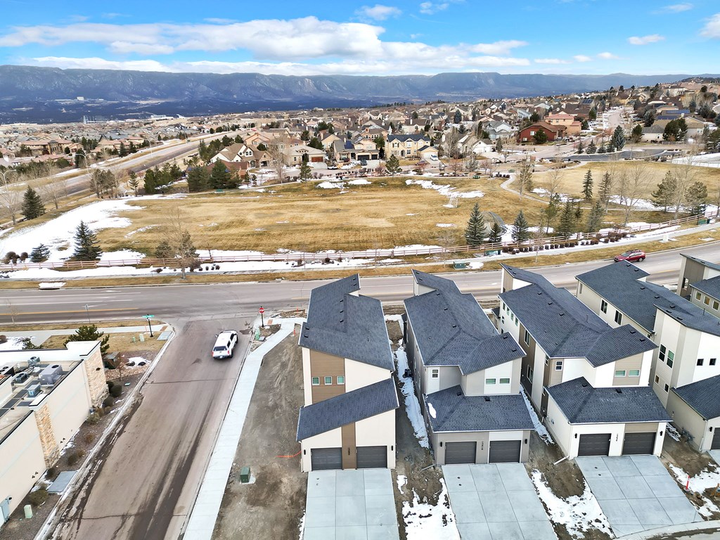 A road with a car driving down it and apartment buildings on the side.