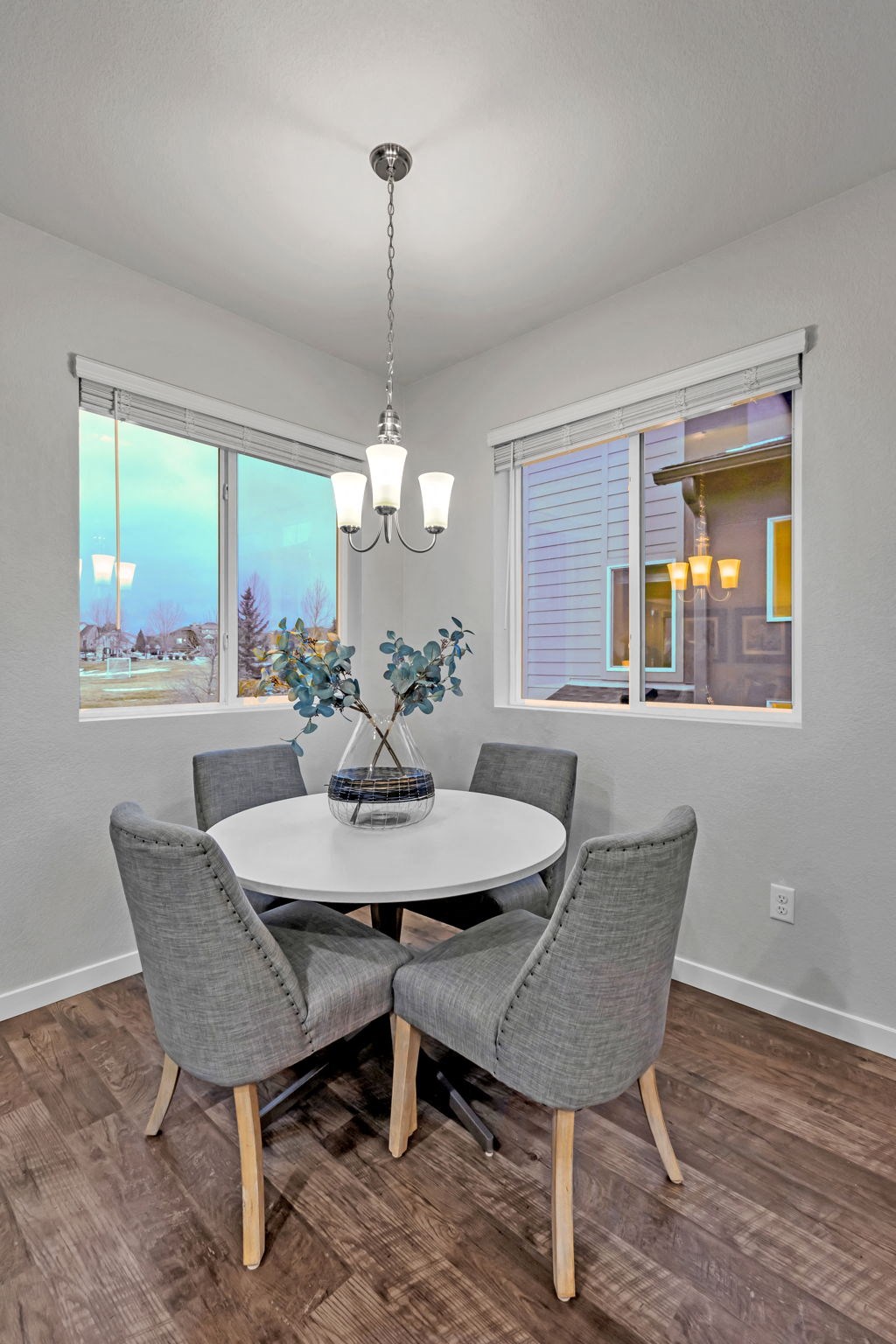 A dining room with a round table and grey chairs.