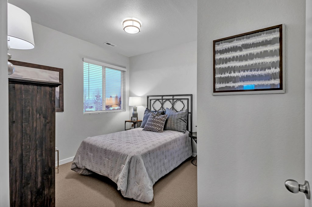 A bedroom with a bed, nightstand, and a painting on the wall.