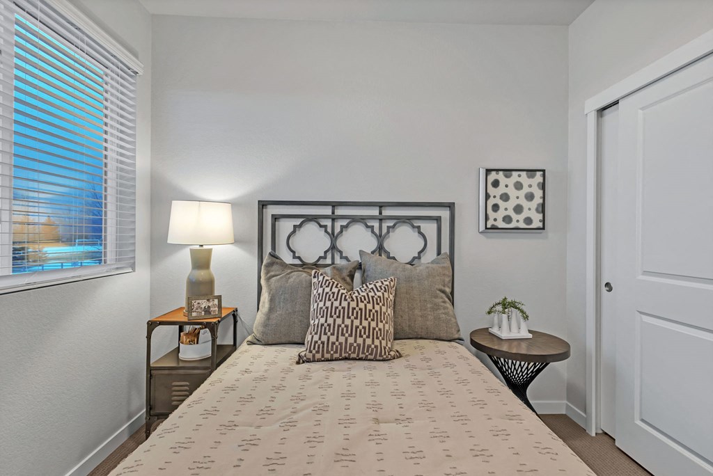 A bedroom with a bed, nightstands, and a window with blinds.