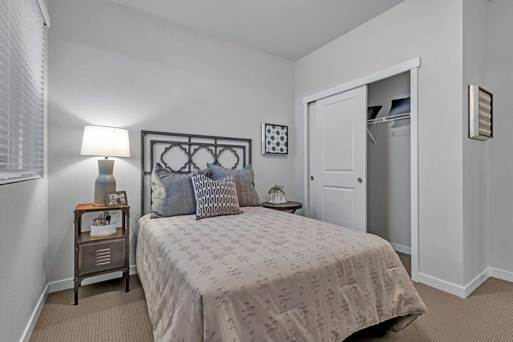 A bedroom with a bed, nightstand, and lamp.