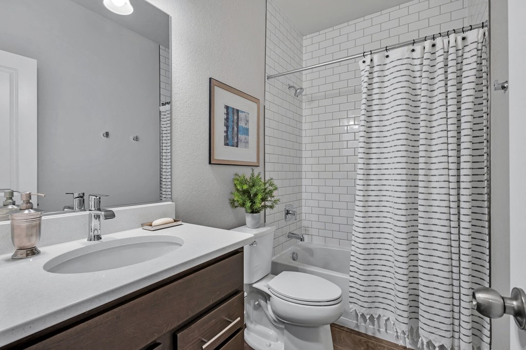 A white bathroom with a toilet, sink, and shower.