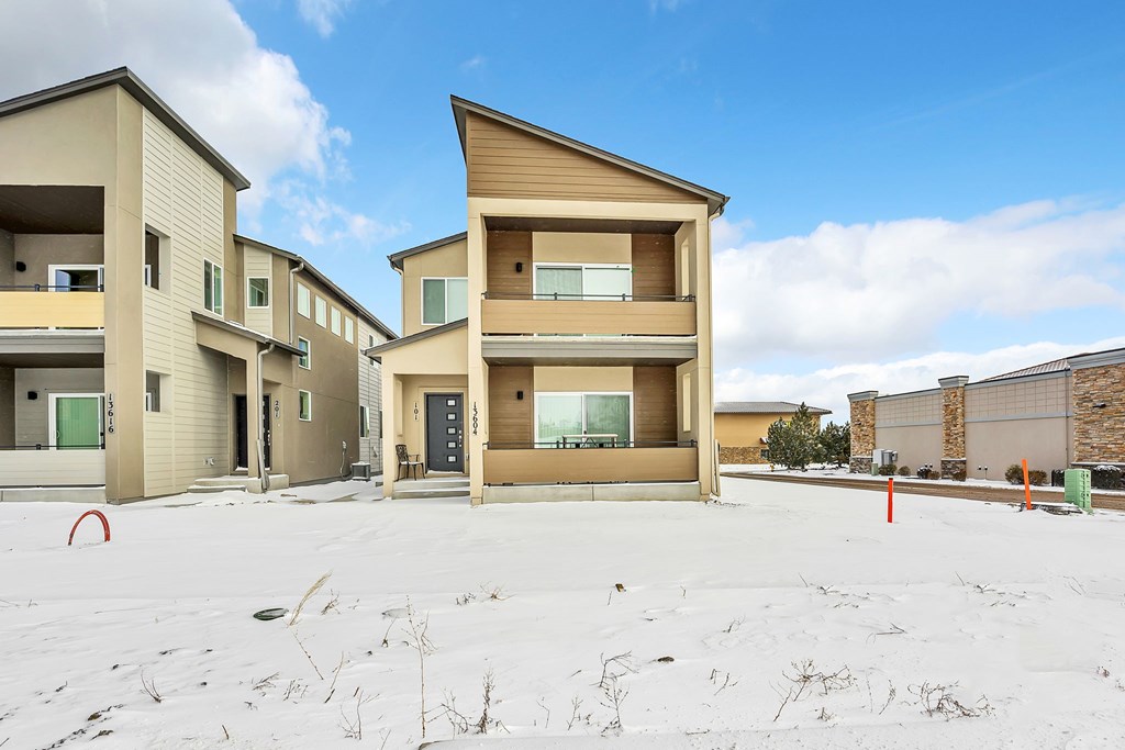 A row of modern houses with a snowy ground in front.