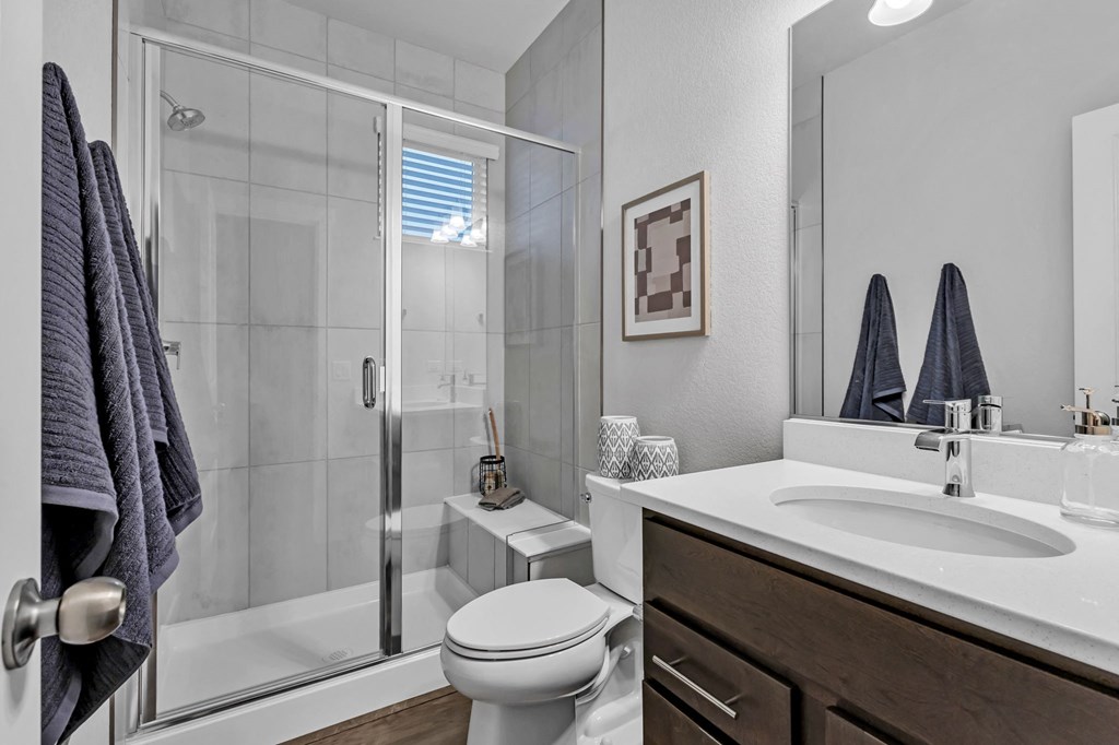 A modern bathroom with a toilet, sink, and shower.