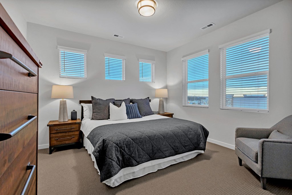 A bedroom with a large bed, a chair, and a dresser.