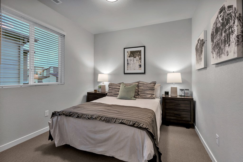 A bedroom with a bed, nightstands, and pictures on the wall.