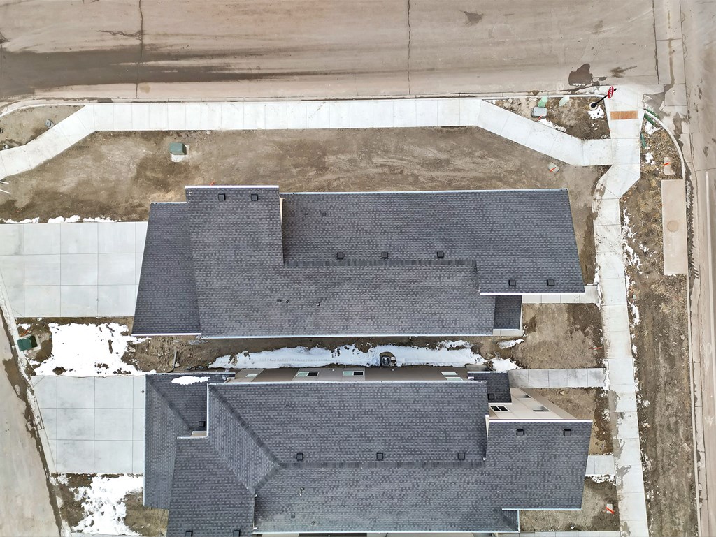 A large building with a grey roof is surrounded by a white fence.