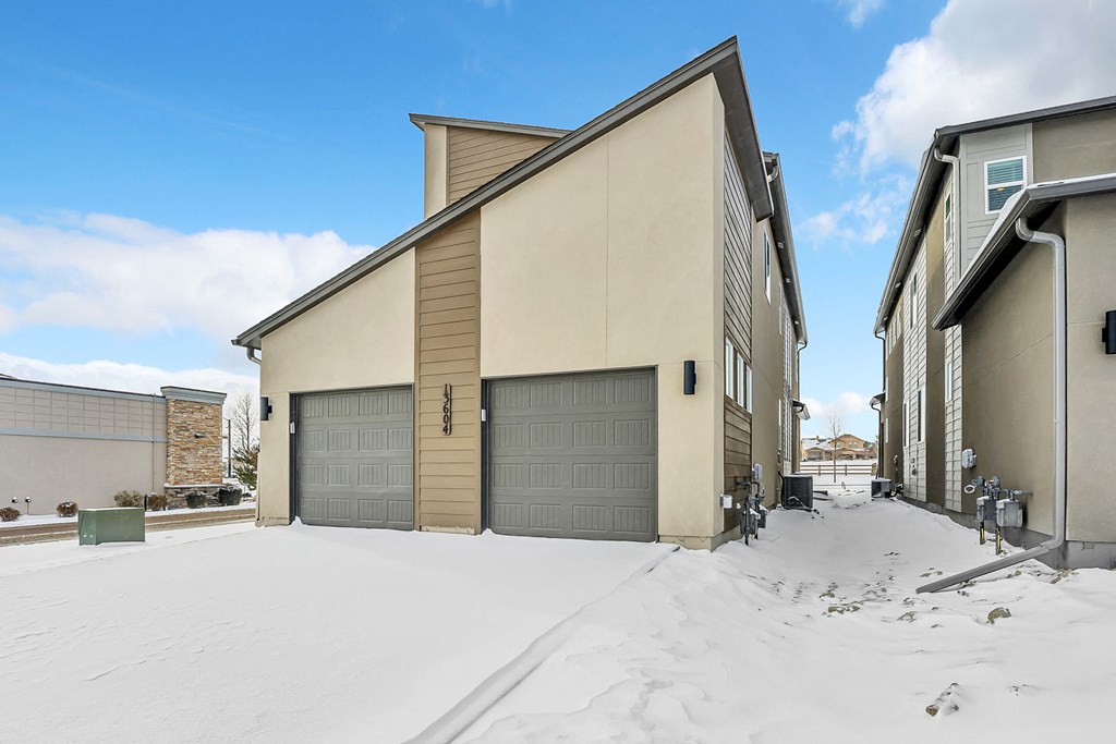 A house with a garage door in the snow.
