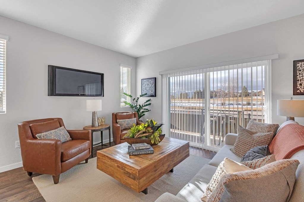 A living room with a brown leather chair, a wooden coffee table, and a flat screen TV mounted on the wall.