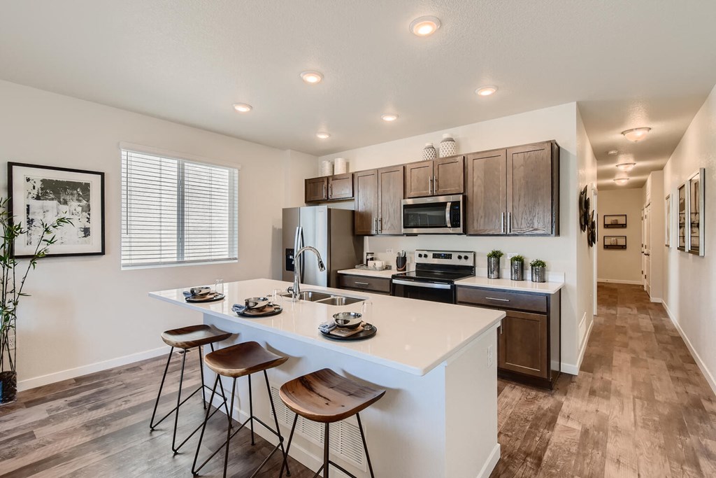 modern kitchen with island and stools in front of stainless steel appliances