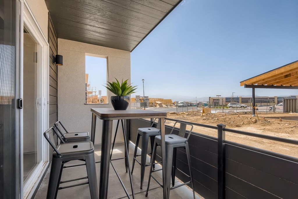 a bar with stools and a table on a balcony with a view
