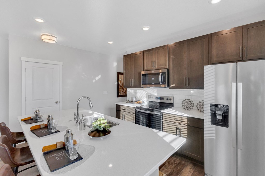 A modern kitchen with a white countertop and stainless steel appliances.