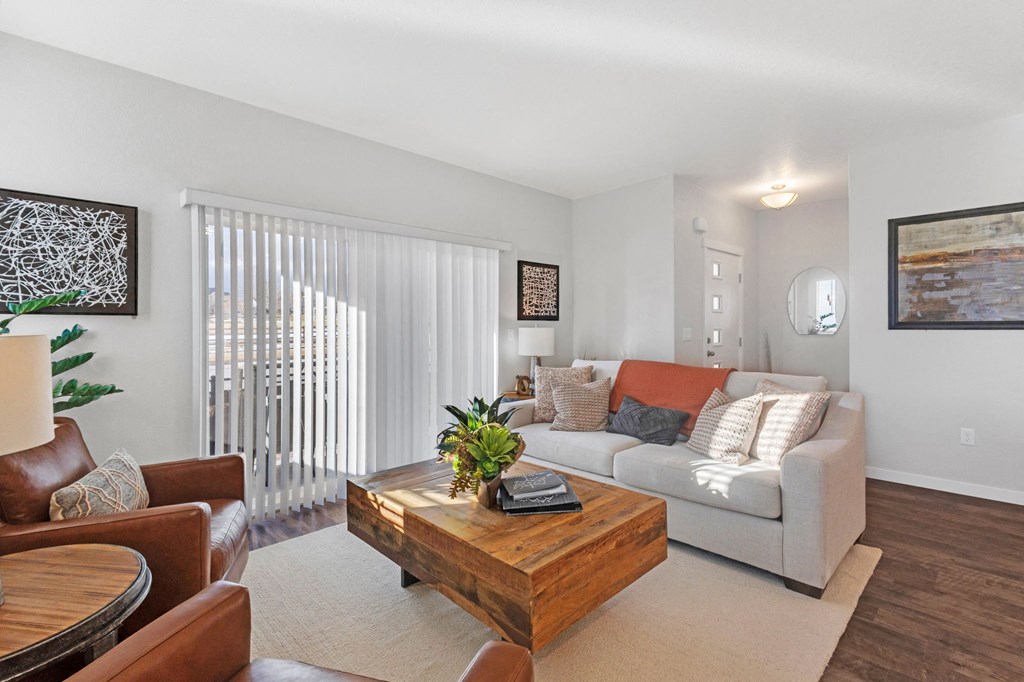A living room with a brown leather chair, a wooden coffee table, and a white couch with orange pillows.