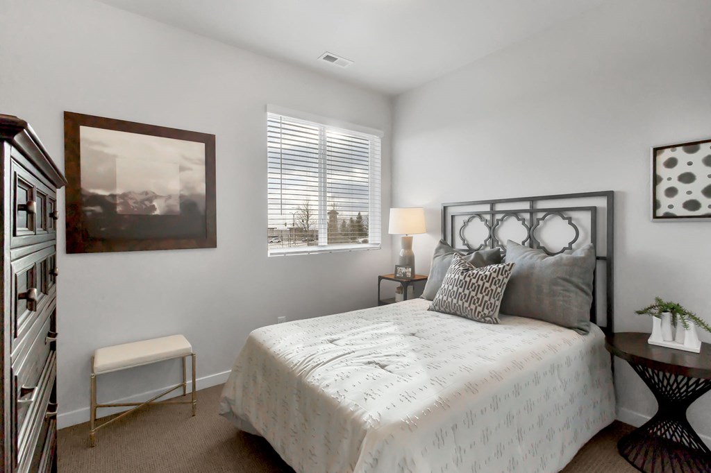 A bedroom with a large bed, a small table, and a painting on the wall.