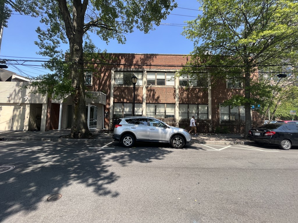 a large brick building with a red roof and a white car parked in front of it