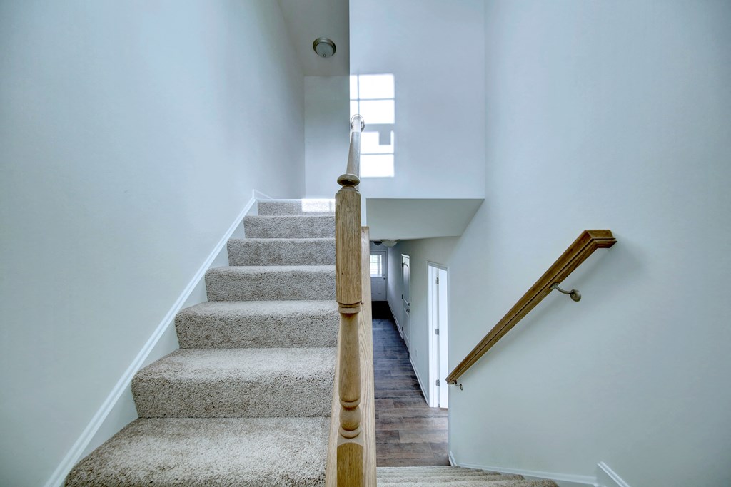 entry foyer with hardwood floors and white door wood rails leading upstairs