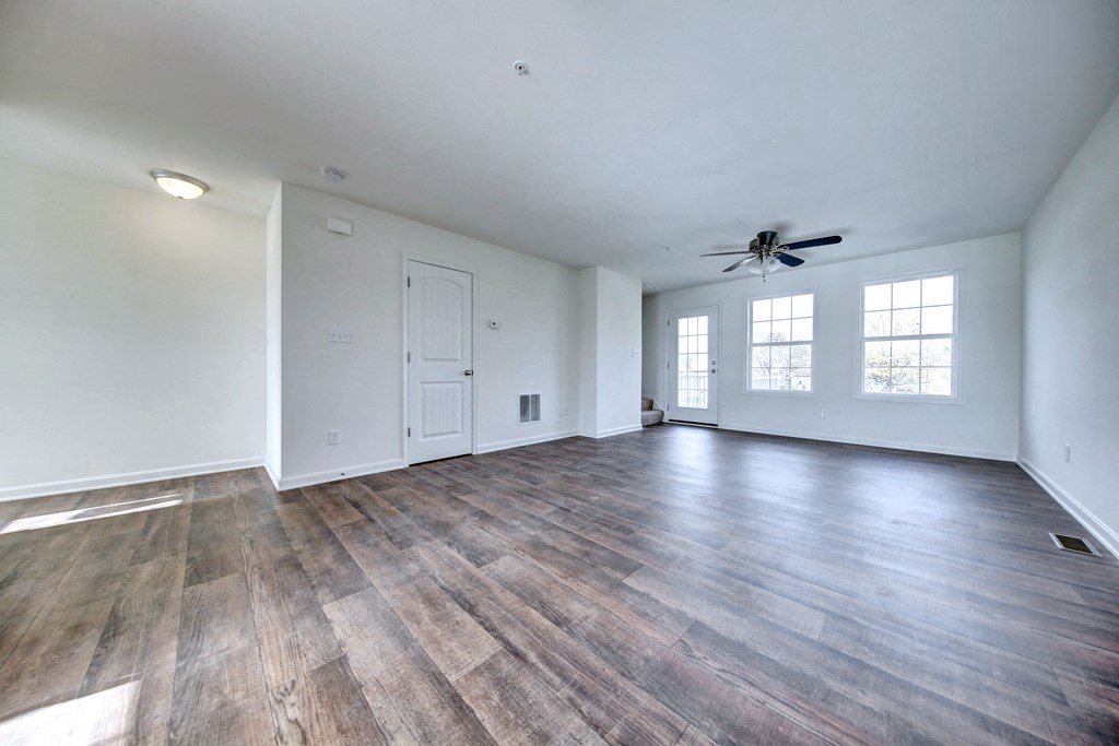 living room with hardwood floors and ceiling fan stairs leading up to the third level