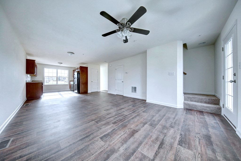 living room with hardwood floors and ceiling fan stairs leading up to the third level