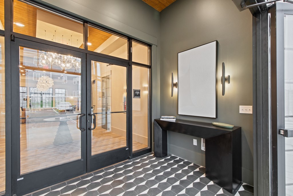 Entrance to a building with glass doors and a black table at Hadley Place Apartments, Pennsylvania
