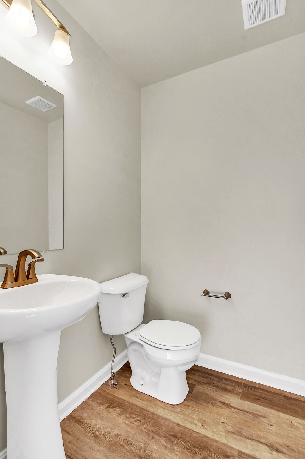 bathroom with hardwood floors and ceramic toilet and sink