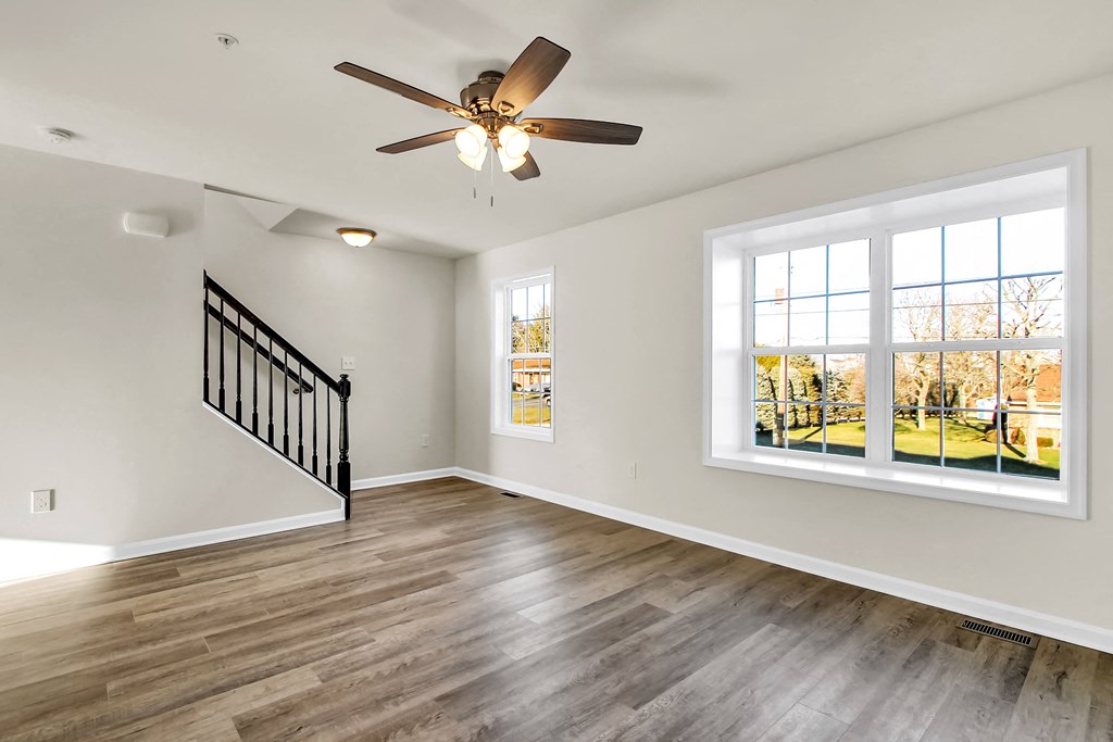 living room with hardwood floors and ceiling fan stairs leading up to the third level