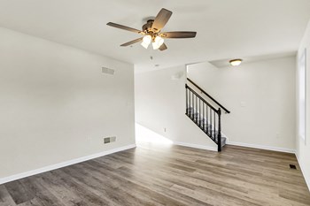 living room with hardwood floors and ceiling fan stairs leading up to the third level - Photo Gallery 4