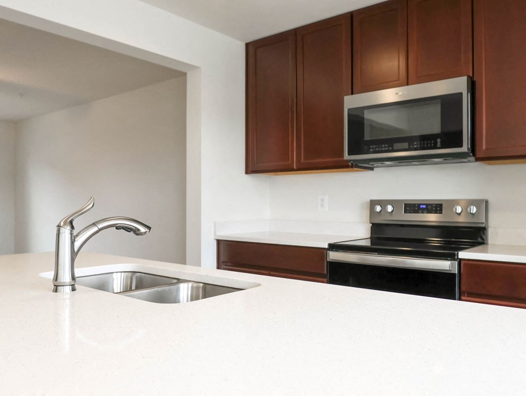 a kitchen with white countertops and dark wood cabinets