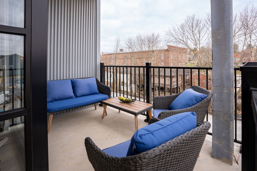 a balcony with chairs and a table with blue pillows at Franklin Square Apartments/Townhomes, New Freedom