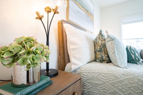 a bedroom with a bed and a table with a vase of flowers  at Franklin Square Apartments/Townhomes, New Freedom, Pennsylvania