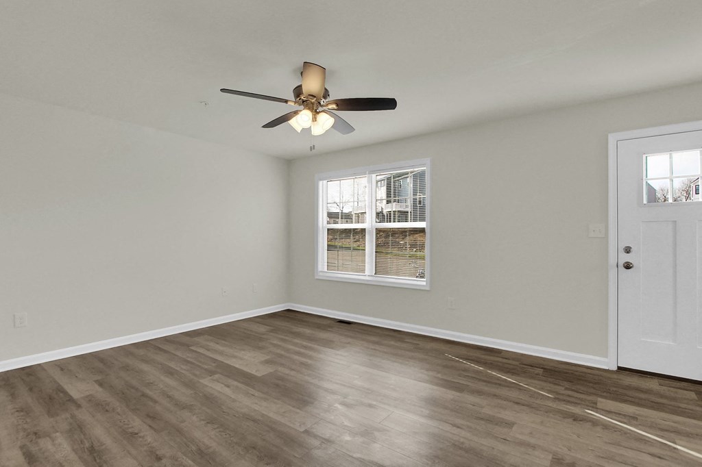 living room with hardwood floors and ceiling fan stairs leading up to the third level