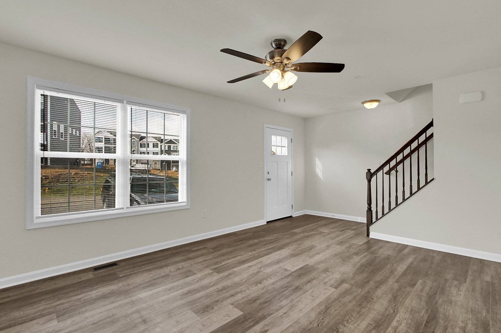 living room with hardwood floors and ceiling fan stairs leading up to the third level