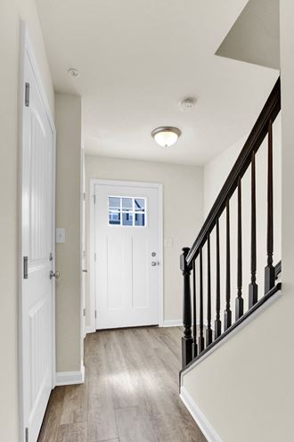 stairwell with wood railing and hardwood floors white front door  at Franklin Square Apartments/Townhomes, New Freedom, PA