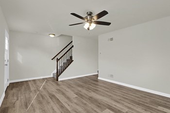 living room with hardwood floors and ceiling fan stairs leading up to the third level - Photo Gallery 3
