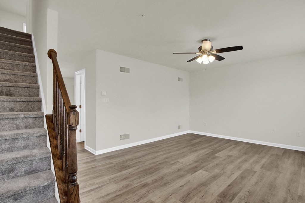 living room with hardwood floors and ceiling fan stairs leading up to the third level
