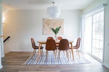 a dining room with white walls and a blue and white rug