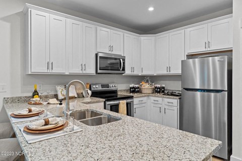 a kitchen with white cabinets and granite countertops at Beckington, Leland, NC