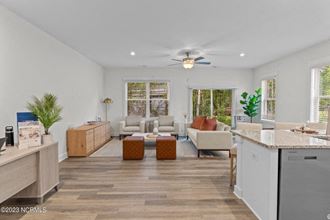 a living room with white walls and a ceiling fan