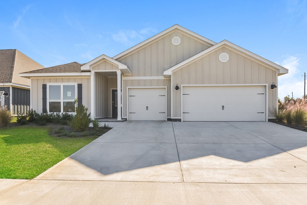 a beige house with two garage doors and a driveway