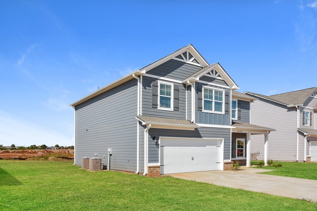 a gray house with a white garage door and a green lawn