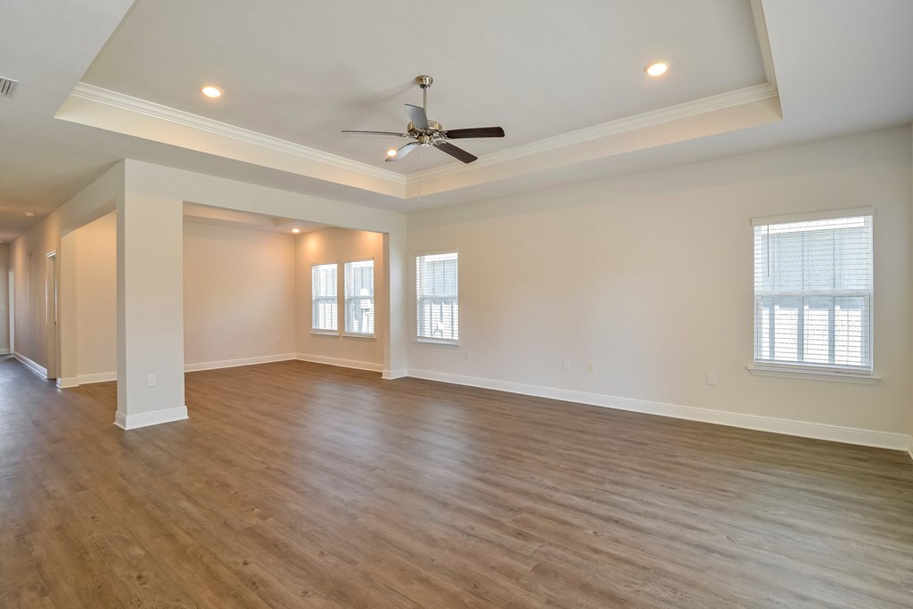 an empty living room with white walls and a ceiling fan