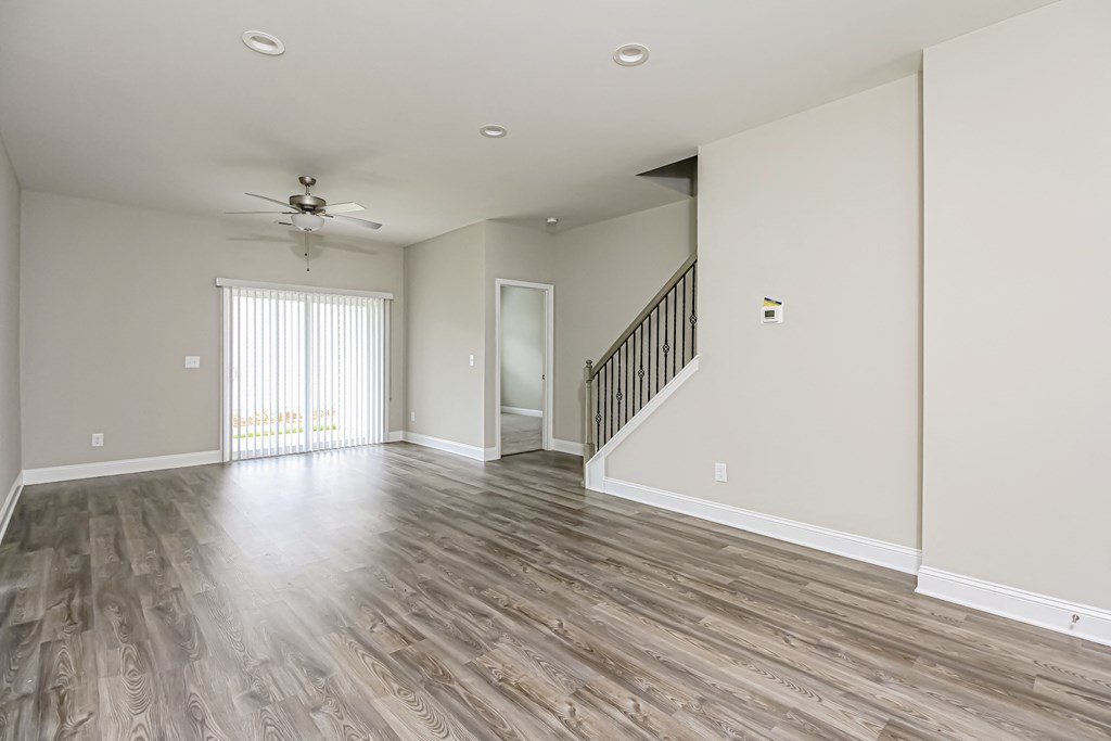 an empty living room with wood flooring and a ceiling fan
