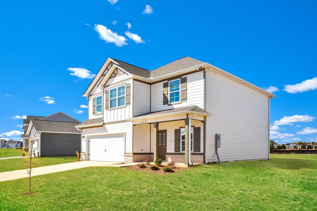 a beige and white house with a yard and a blue sky