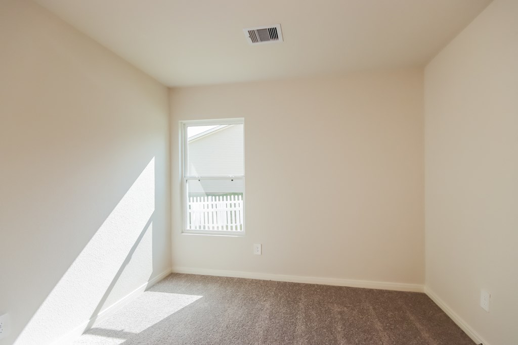an empty living room with a window and a carpet
