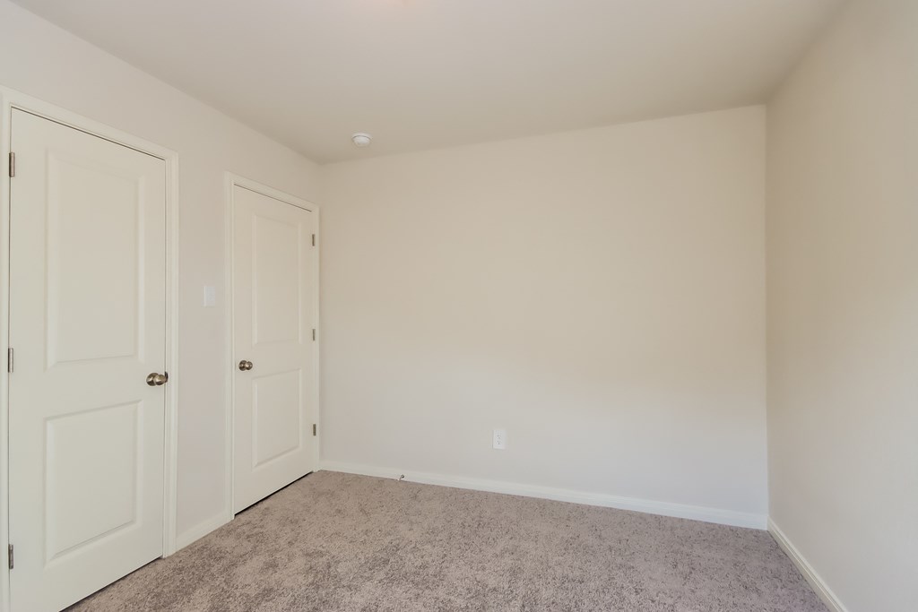 a bedroom with two doors and a carpeted floor