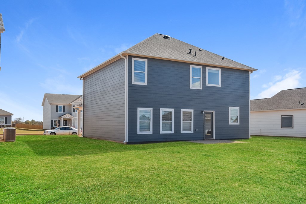 the backyard of a house with a green lawn and a blue house