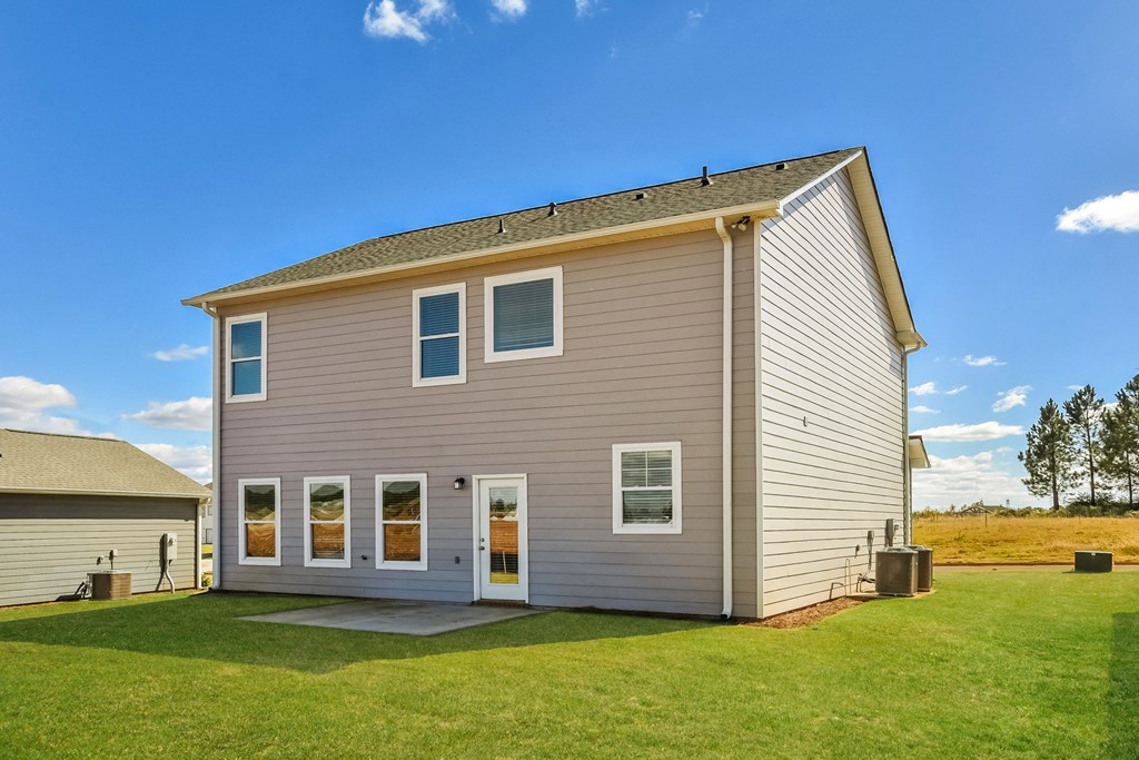 the back of a house on a green lawn and a blue sky
