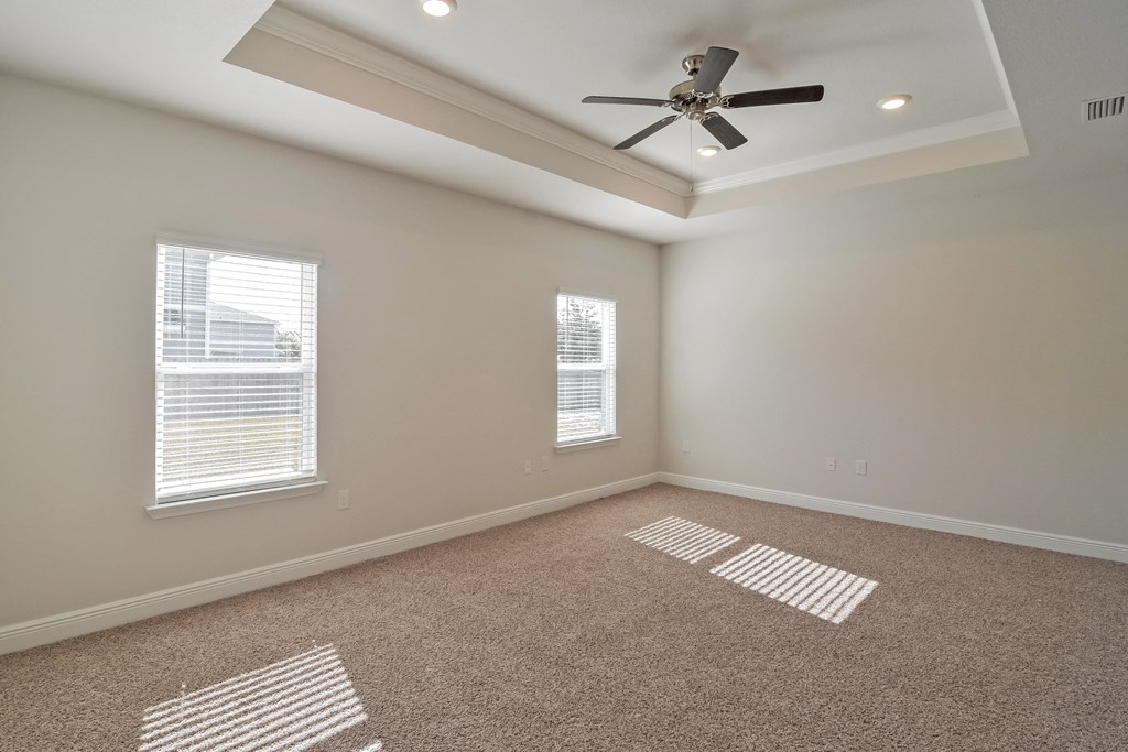 an empty living room with a ceiling fan and two windows