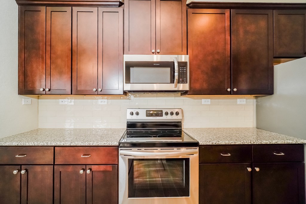 a kitchen with brown cabinets and white appliances and granite counter tops